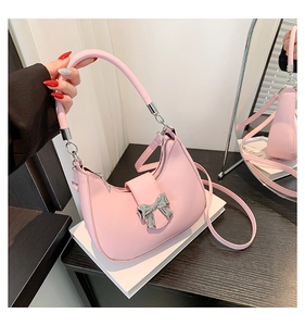 Détail du sac demi-lune rose avec nœud métallique et double bandoulière amovible