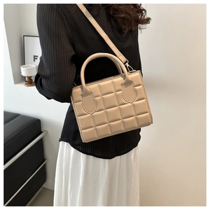 Chic beige quilted square bag styled with a white skirt and pleated top for elegant look