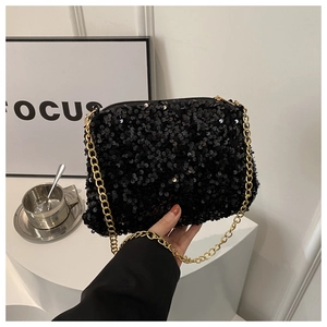 Detail of a chic black sequin crossbody bag with a slim gold chain shoulder strap