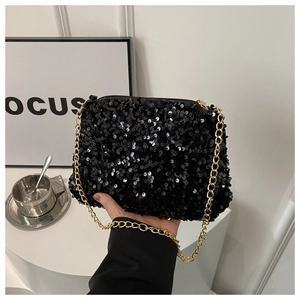 Detail of black sequin shoulder bag with golden chain strap on a modern minimalist display