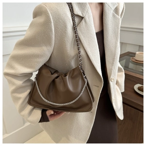 Detail of brown pleated cloud bag with silver metal chain and soft PU leather texture