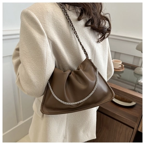 Brown pleated drawstring bucket bag with silver chain strap shown on a model