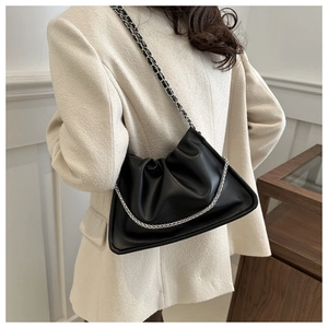 Detail of black pleated cloud bag with silver chain strap on light beige blazer