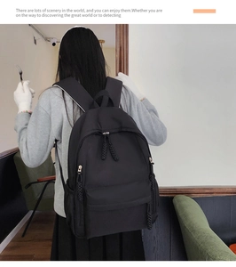 Detail of a large black nylon travel backpack showing side pockets and woven zip pulls
