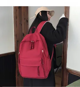 Detailed back view of a large red nylon travel backpack worn by a female model outdoors