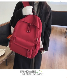 Detail of red water-resistant nylon backpack featuring thick woven rope zipper pulls