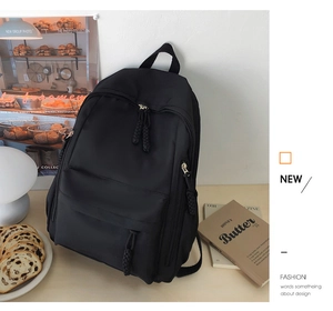 Minimalist black student backpack with woven zipper pulls in a cozy cafe setting