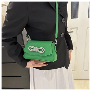 Détail d'un sac à bandoulière vert vif orné d'un nœud étincelant en strass argentés