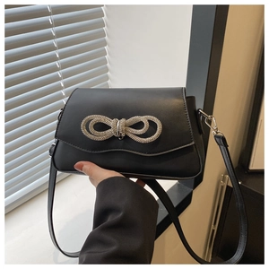 Détail d'un sac à bandoulière noir élégant avec un nœud en diamant et une fine lanière