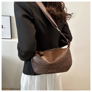 Close-up of brown faux leather crescent bag with adjustable jacquard woven shoulder strap