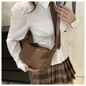 Detail of adjustable chevron strap and gold rivet accents on a brown soft leather bag