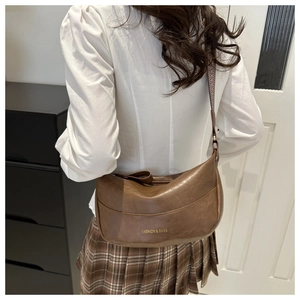 Rear view of model wearing a large brown retro hobo bag with gold fashion lettering