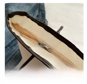 Detailed top view of a cream tote bag featuring a smooth metal zipper and brown trim