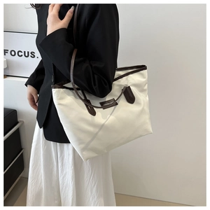Close-up of white nylon tote bag featuring brown leather straps and fashion logo patch
