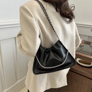 Elegant black ruched bucket bag with silver chain strap shown in a lifestyle setting