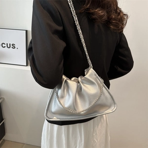 Chic silver metallic pleated cloud bucket bag with chain strap worn by a model