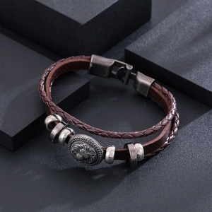 Macro detail of men's leather bracelet with silver lion head emblem and woven strap