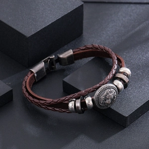 Detail of vintage lion head charm on multi-layer braided dark brown leather bracelet