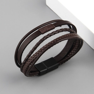 Close-up of multilayered brown leather bracelet with braided cords and matte magnetic clasp