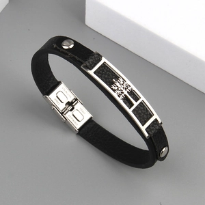 Detail of stainless steel life tree charm on black leather bracelet with buckle closure