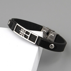 Black leather tree of life bracelet with stainless steel buckle on white geometric stand