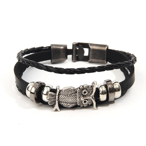 Dettaglio del bracciale vintage in pelle nera con ciondolo a gufo e inserti in metallo