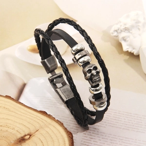 Dettaglio del bracciale multistrato in pelle intrecciata con teschio e chiusura in metallo