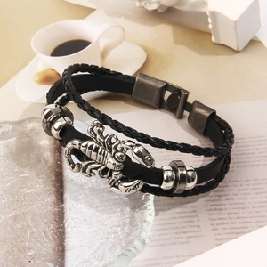 Dettaglio del bracciale multistrato in pelle intrecciata con grande ciondolo a scorpione