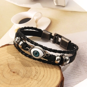 Dettaglio del bracciale a tre strati in pelle nera intrecciata con ciondolo malocchio