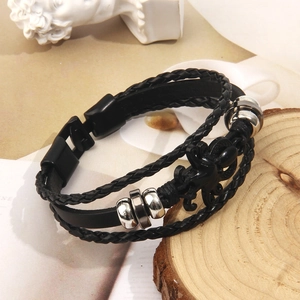 Detail of men's leather bracelet with octopus charm and woven strands on wood