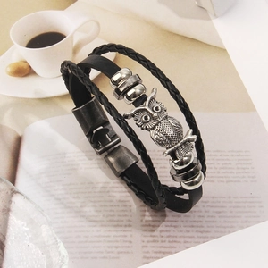 Dettaglio del bracciale in pelle multistrato con ciondolo a civetta in metallo