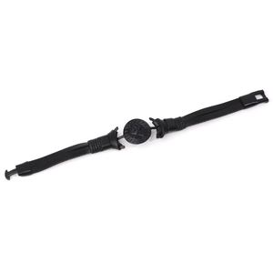 Macro detail of men's black braided leather bracelet featuring an embossed skull metal charm