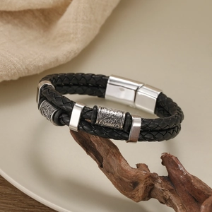 Detail of double-layer woven black leather bracelet with carved metal beads and magnetic clasp