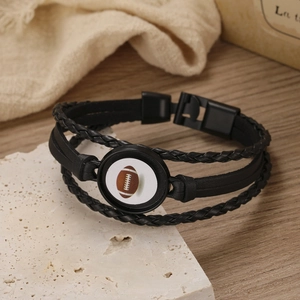 Detail of multi-layer black braided leather bracelet featuring an American football charm