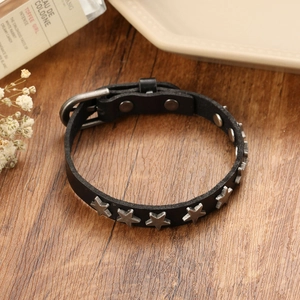 Gros plan d'un bracelet punk en cuir noir avec rivets étoiles argentés sur bois sombre