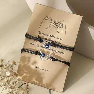 Detail of evil eye braided bracelets with star and moon charms on a kraft paper card