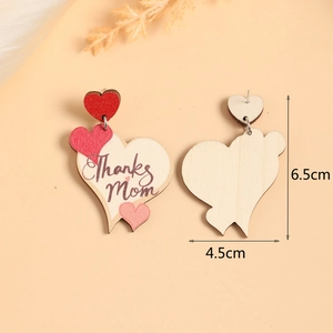 Detail view of wooden heart earrings with Thanks Mom engraving and tiered design