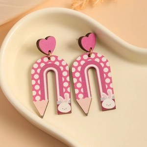 Pink wooden pencil U-shaped earrings with rabbit prints and heart studs on a tray