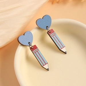 Detail of creative pencil drop earrings with blue heart studs on ceramic dish