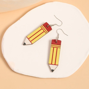 Détail de boucles d'oreilles en bois en forme de crayon sur pierre blanche et fond pêche
