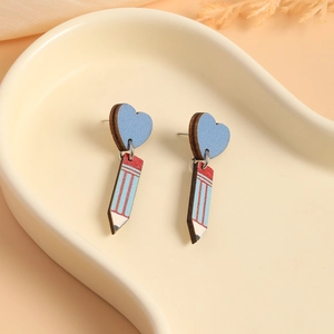 Macro view of blue heart studs and pencil wood earrings on a ceramic tray