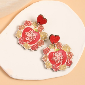 Détail de boucles d'oreilles Fête des Mères en bois avec cœur et motif pomme sur plateau