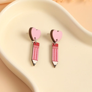 Close-up of creative pink wooden pencil and heart earrings on a ceramic display tray