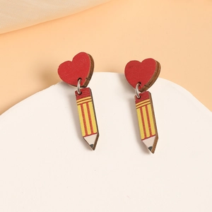 Close-up of wooden heart and pencil drop earrings on a minimalist white platform