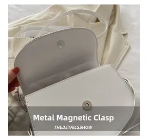Detail of the high-quality magnetic metal clasp on a white quilted crossbody bag