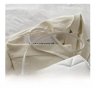Detail showing white quilted crossbody bag with adjustable strap and stitching texture