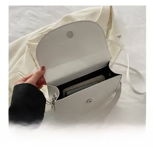 Internal capacity of white crossbody bag holding a smartphone and small wallet