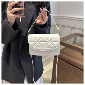 White quilted shoulder bag with triangular pattern worn on a dark blazer outfit