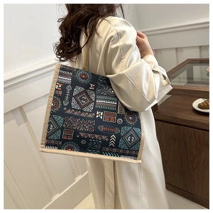 Close-up of ethnic tribal pattern tote bag with woven brown trim and long shoulder strap