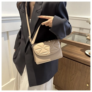 Detailed view of a beige quilted crossbody bag showing geometric pattern and strap